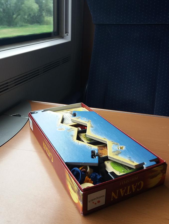 Catan-peruspeli pakattuna lisäosan laatikkoon, junan pöydällä