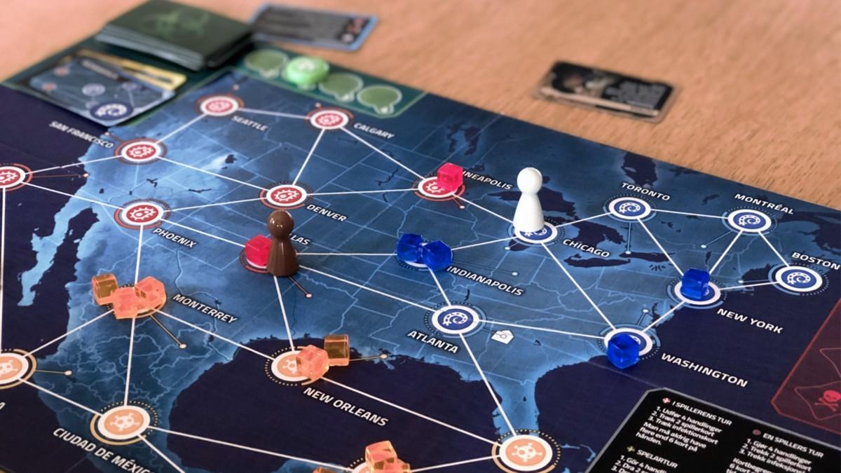 Lähikuva Pandemic: Hot Zone – North American pelilaudasta, joka kuvaa Yhdysvaltoja. Laudalla on valkoinen nappula Chicagossa ja ruskea nappula Dallasissa. Dallasissa ja Minneapolisissa on punaiset tautikuutiot, Monterreyssä, New Orleansissa ja Kuubassa on useampi oranssi, Indianapolisissa, Washingtonissa ja New Yorkissa on sinisiä.