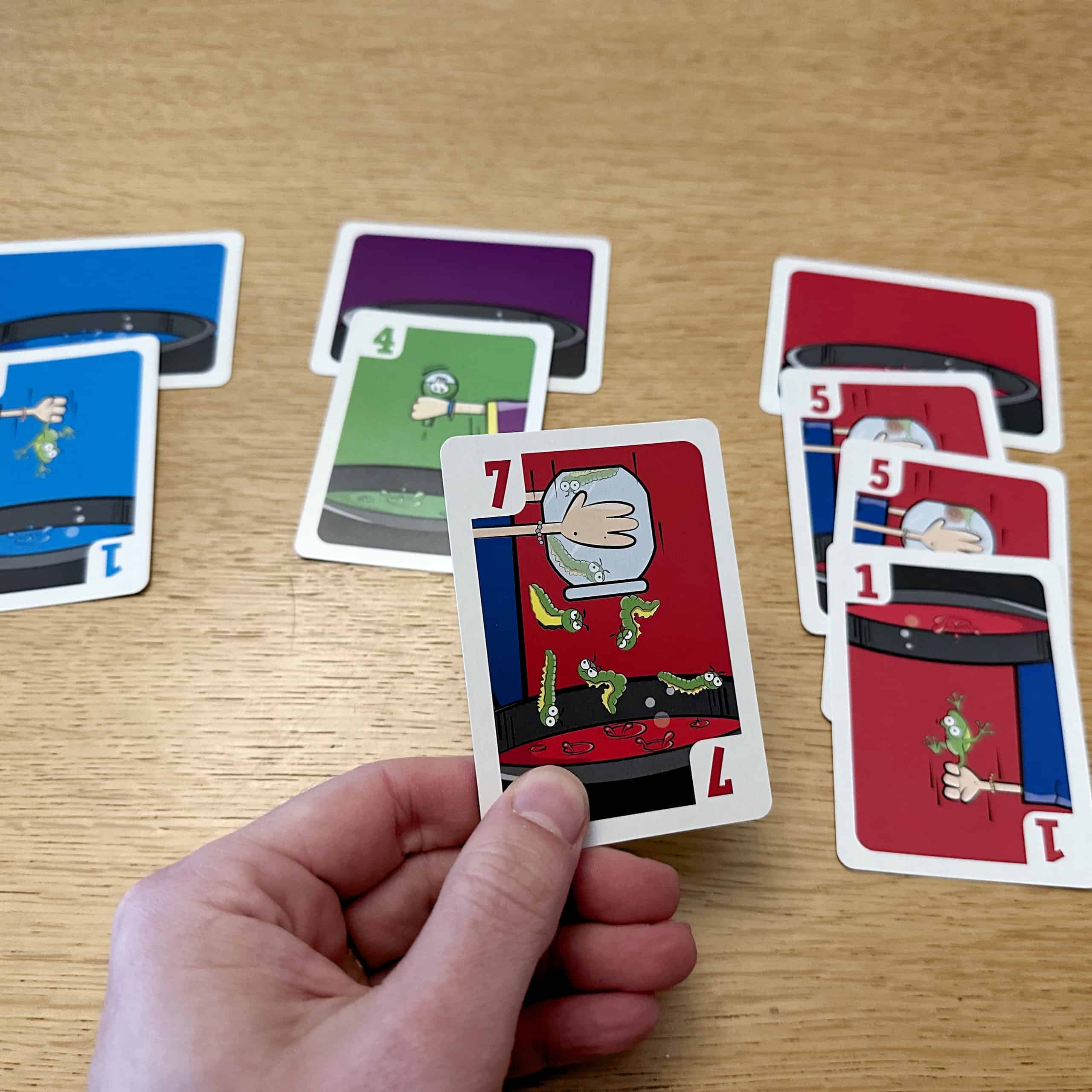 Punainen pata, jossa on kortit 5, 5, ja 1 ja kädessä punainen 7.