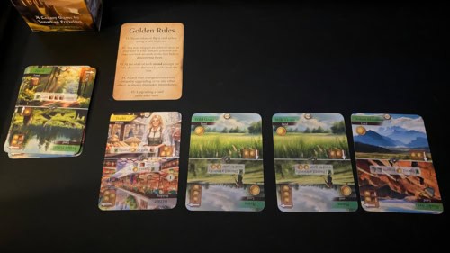 Kingdom Legacy -pelin alkutilannetta: valtakunnassa on kauppias, kaksi ruohokenttää ja kaukaisia vuoria. Vieressä on pakka, jossa on päällä metsä. Golden Rules -kortti tiivistää pelin viisi perussääntöä.
