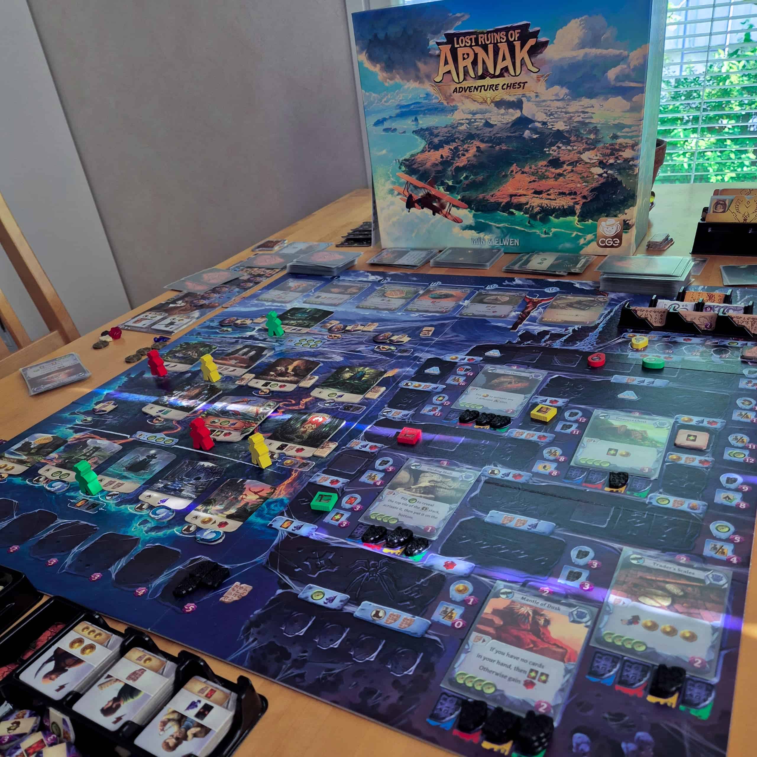 Lost Ruins of Arnak: Adventure Chest -pelin laatikko ja pelilauta. Lauta on iso ja täynnä kortteja ja erilaisia nappuloita.