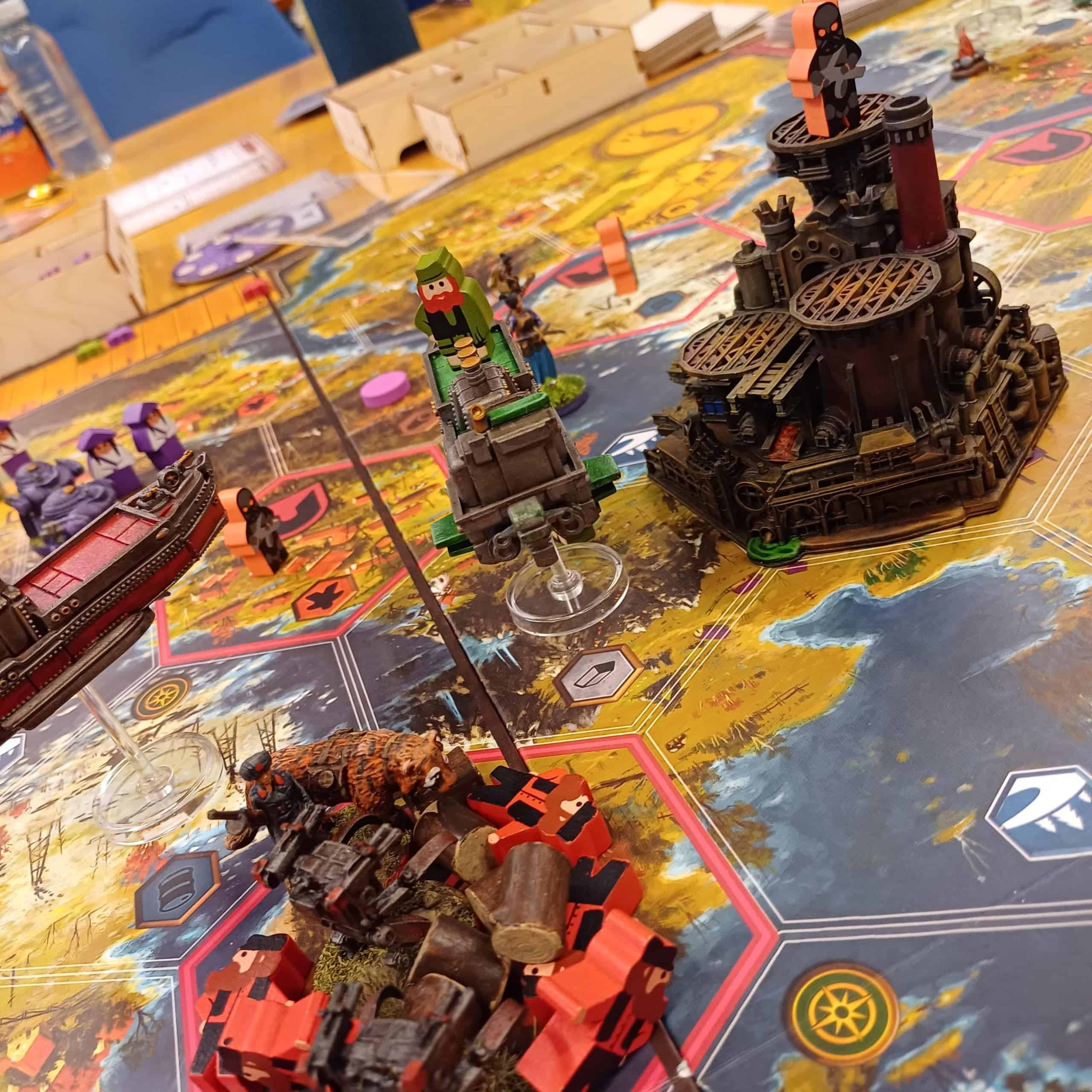 Lähikuva Scythe: Rise of Fenris -pelin laudasta. Laudalla lentelee ilmalaivoja ja laudan keskellä oleva tehdas on upea 3d-tulostettu ja maalattu rakennelma.