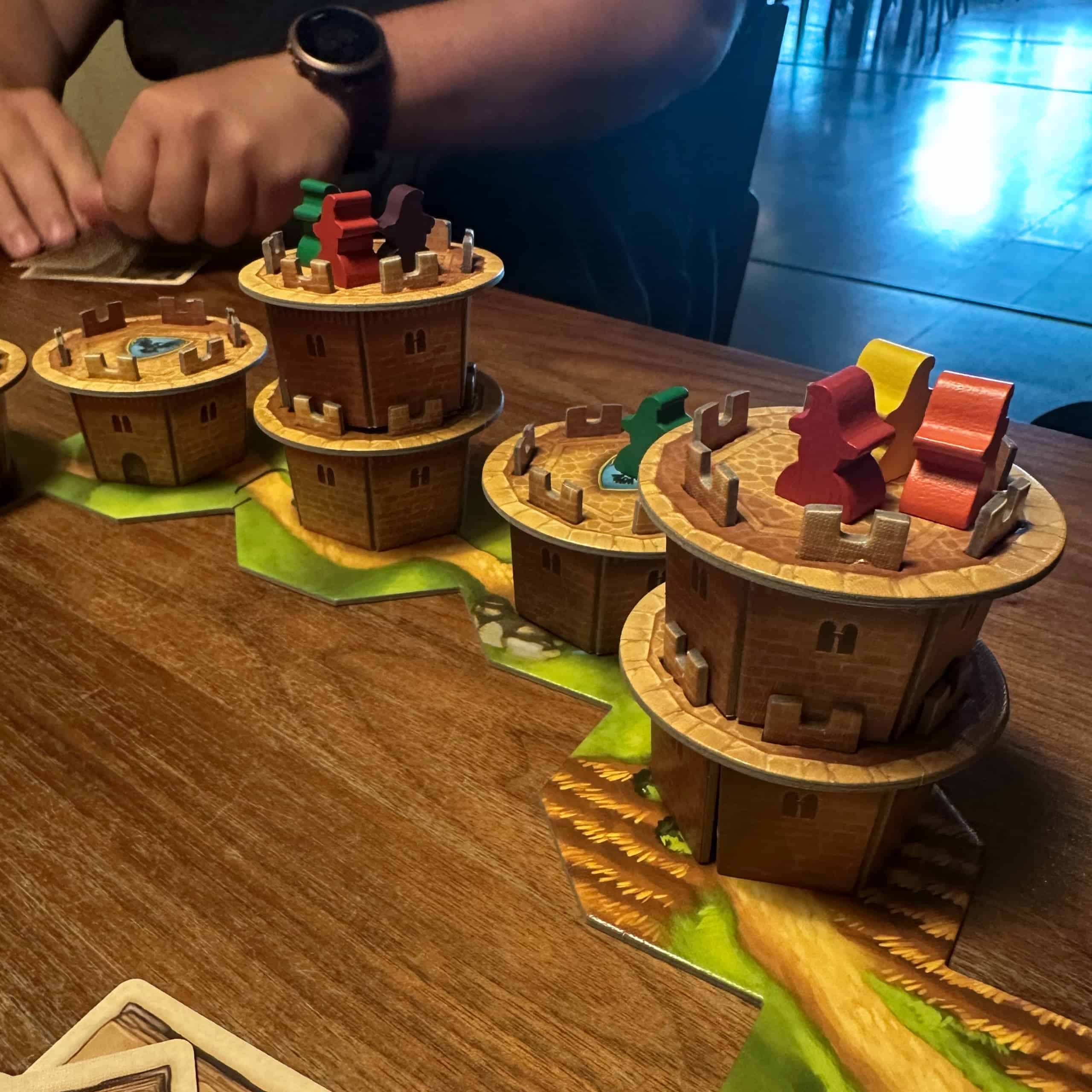 Wandering Towers -pelin pahvitorneja radalla. Torneja on jossain ruuduissa yksi, toisissa kaksi, ja tornien päällä (ja luultavasti myös sisällä) on pelaajien velhonappuloita.