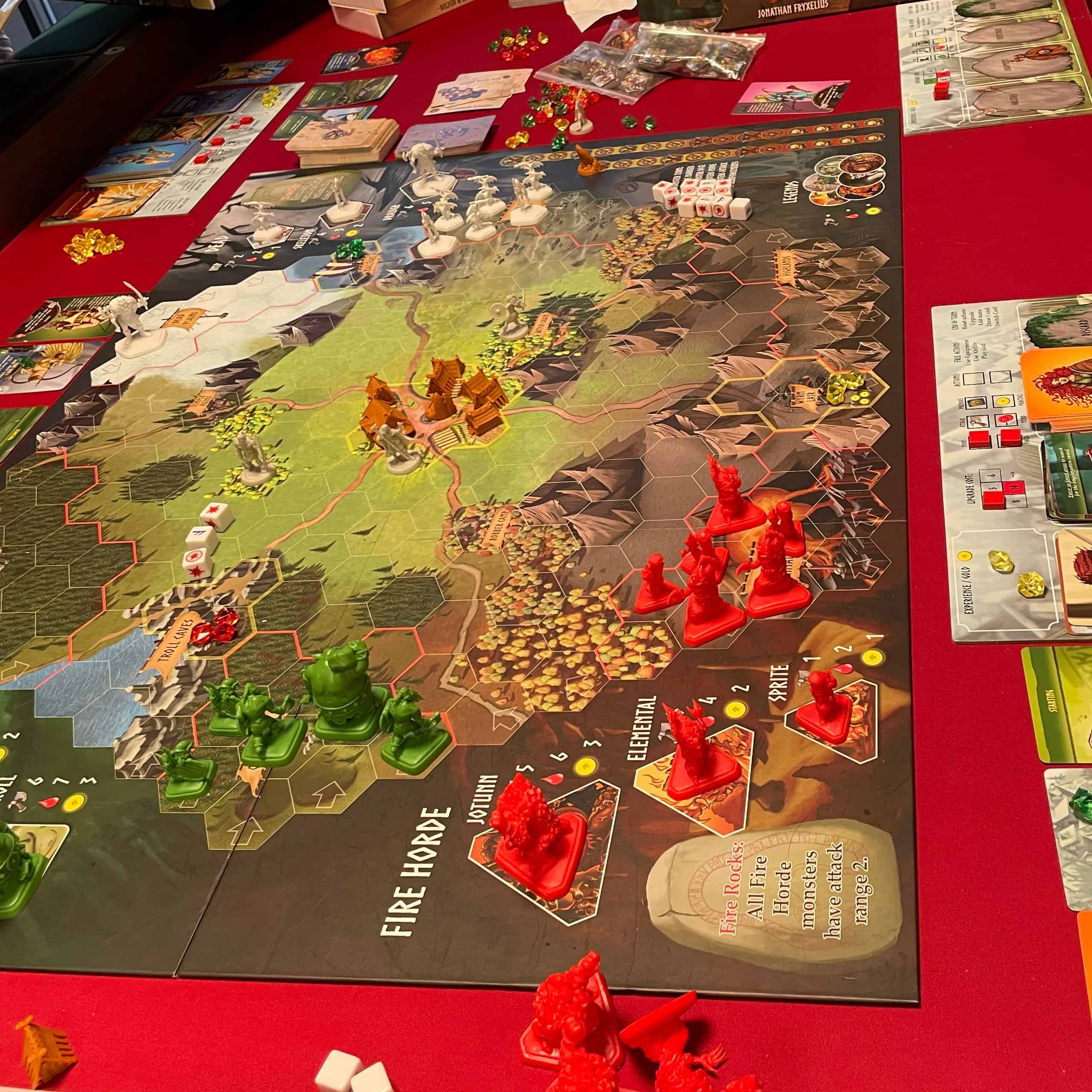 Pelilaudalla on hirviöinä värikkäitä muovifiguureja. Etualalla on punaisia Fire Horde -hirviöitä ja vihreitä peikkoja.