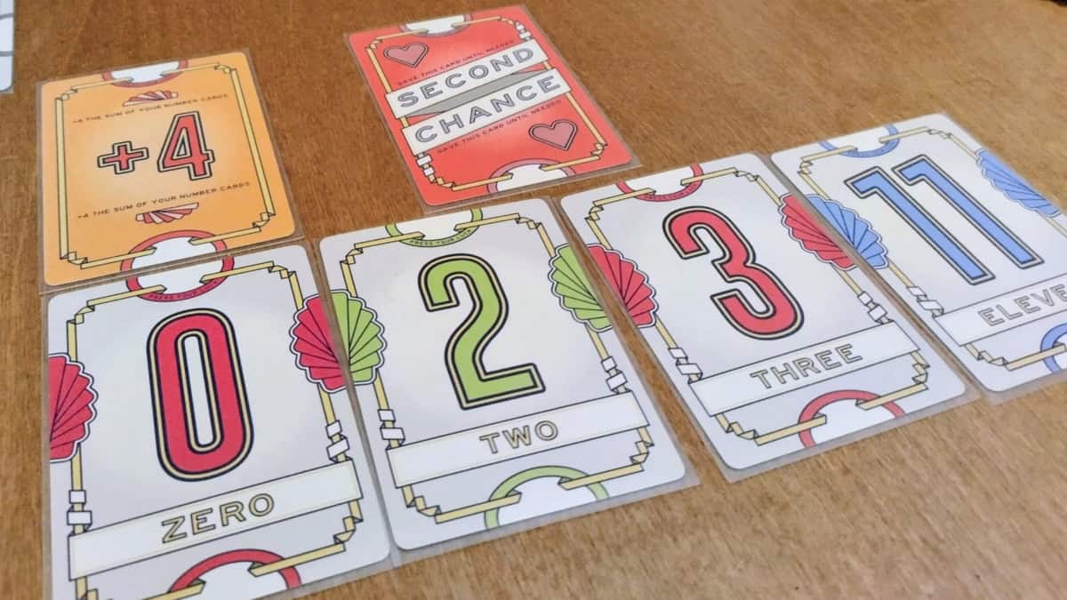 Flip 7 -korttipelin kortteja: numerokortit 0, 2, 3 ja 11, +4-kortti ja Second Chance -kortti.