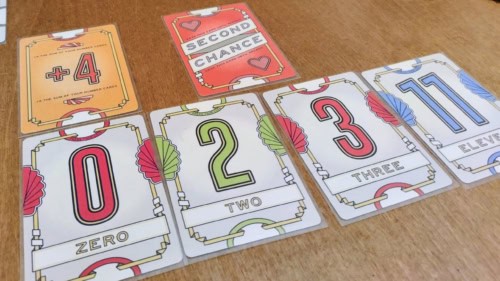 Flip 7 -korttipelin kortteja: numerokortit 0, 2, 3 ja 11, +4-kortti ja Second Chance -kortti.