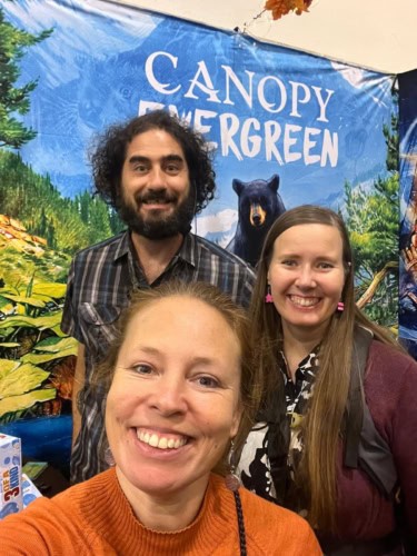 Selfie Canopy: Evergreen -pelin mainosbannerin edessä.