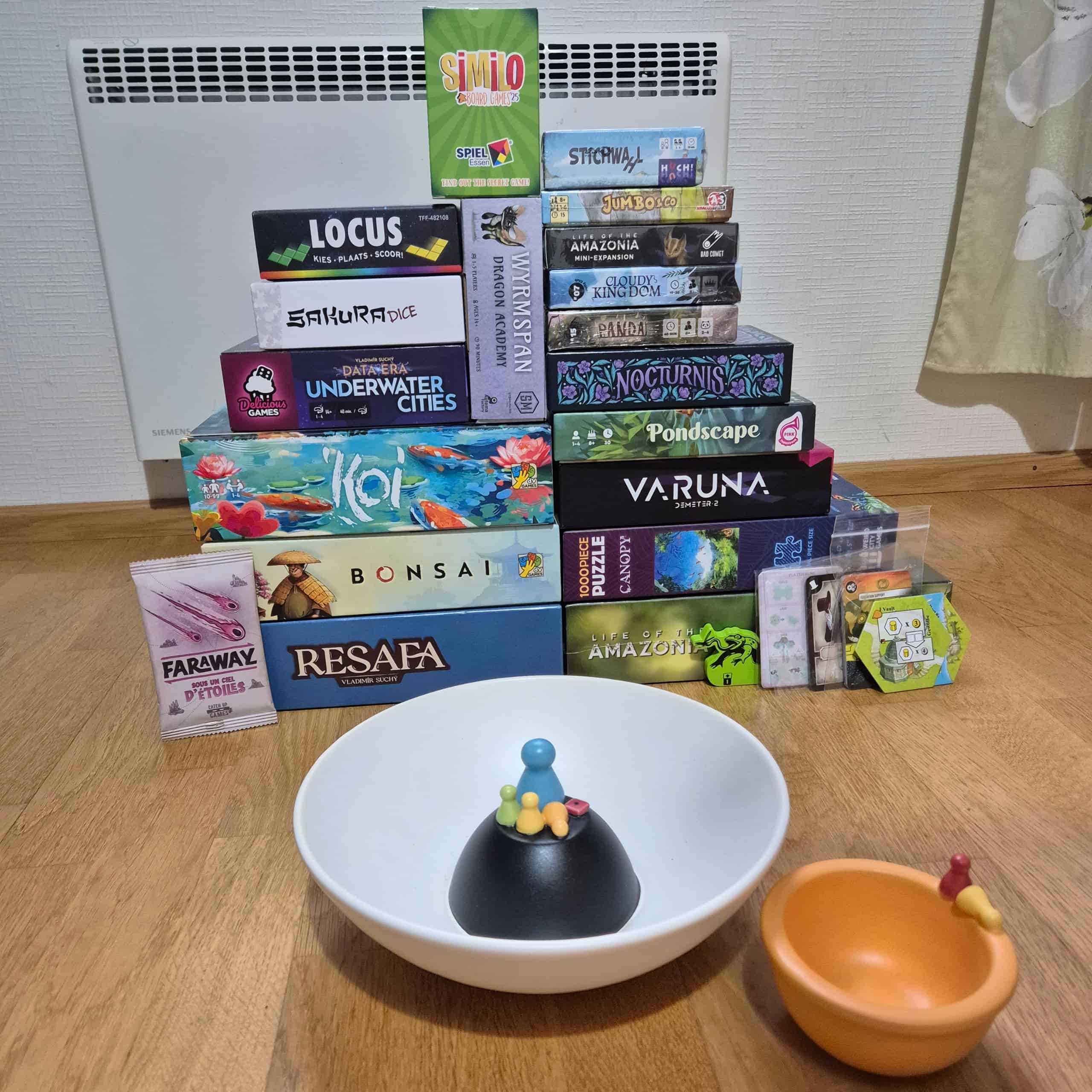 Vilman Spiel-ostokset: Farawayn lisäri, Resafa, Life of the Amazonia, promoja, Bonsai, Canopy-palapeli, Koi, Varuna, Pondscape, Underwater Cities: Data Era, Nocturnis, Sakura Dice, Wyrmspan: Dracon Academy, Panda, Cloudy Kingdom, Locus, Life of the Amazonia -minilisäri, Jumbo & Co, Similo Board Games 2025, Stichwahl ja etualalla pari lautapelikoristeltua kippoa.