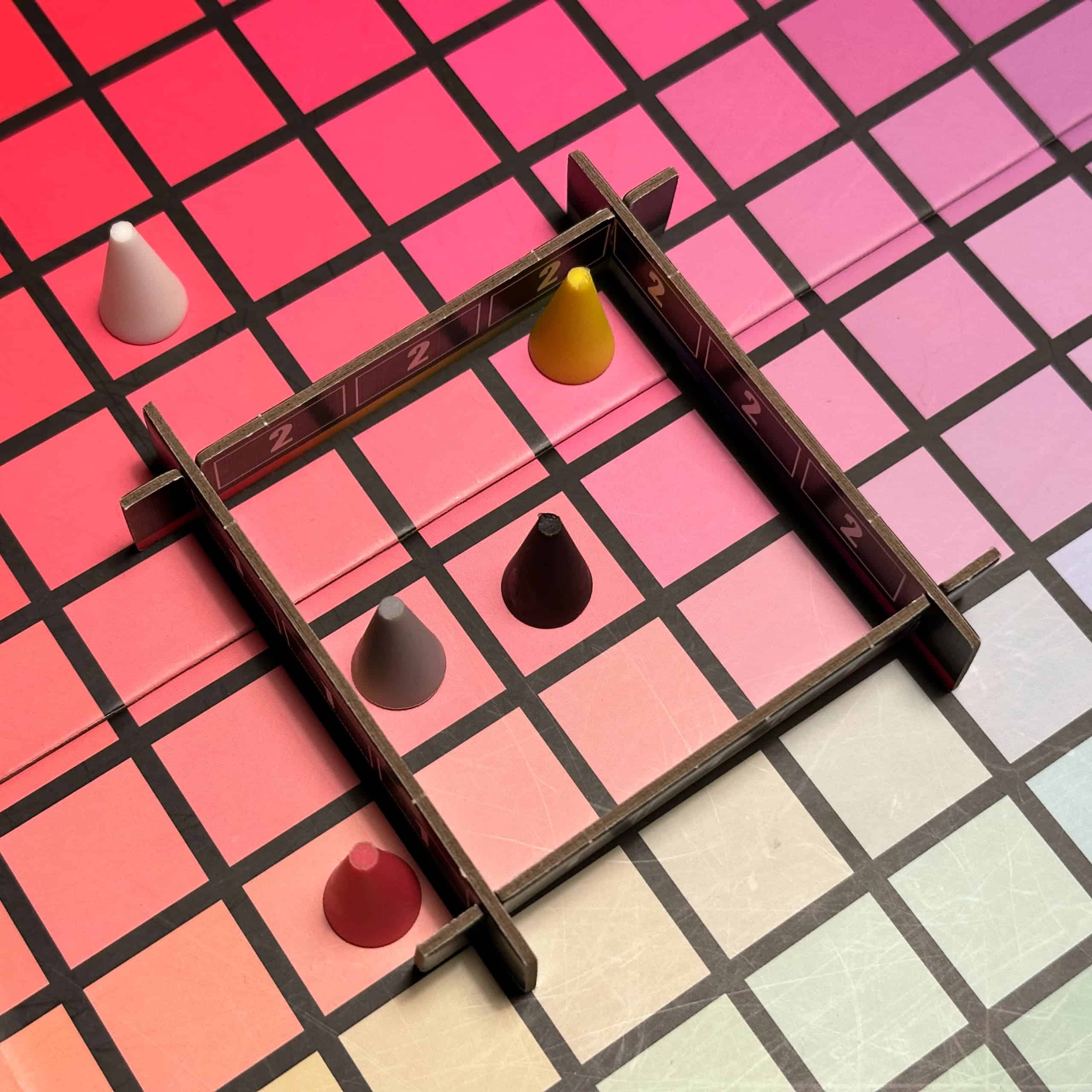 Pelin 3×3-pistekehikko laudalla, nappuloita sen sisällä ja ympärillä. Musta on kehikon keskellä, harmaa ja keltainen sisällä, punainen ulkopuolella vieressä ja valkoinen kauempana.