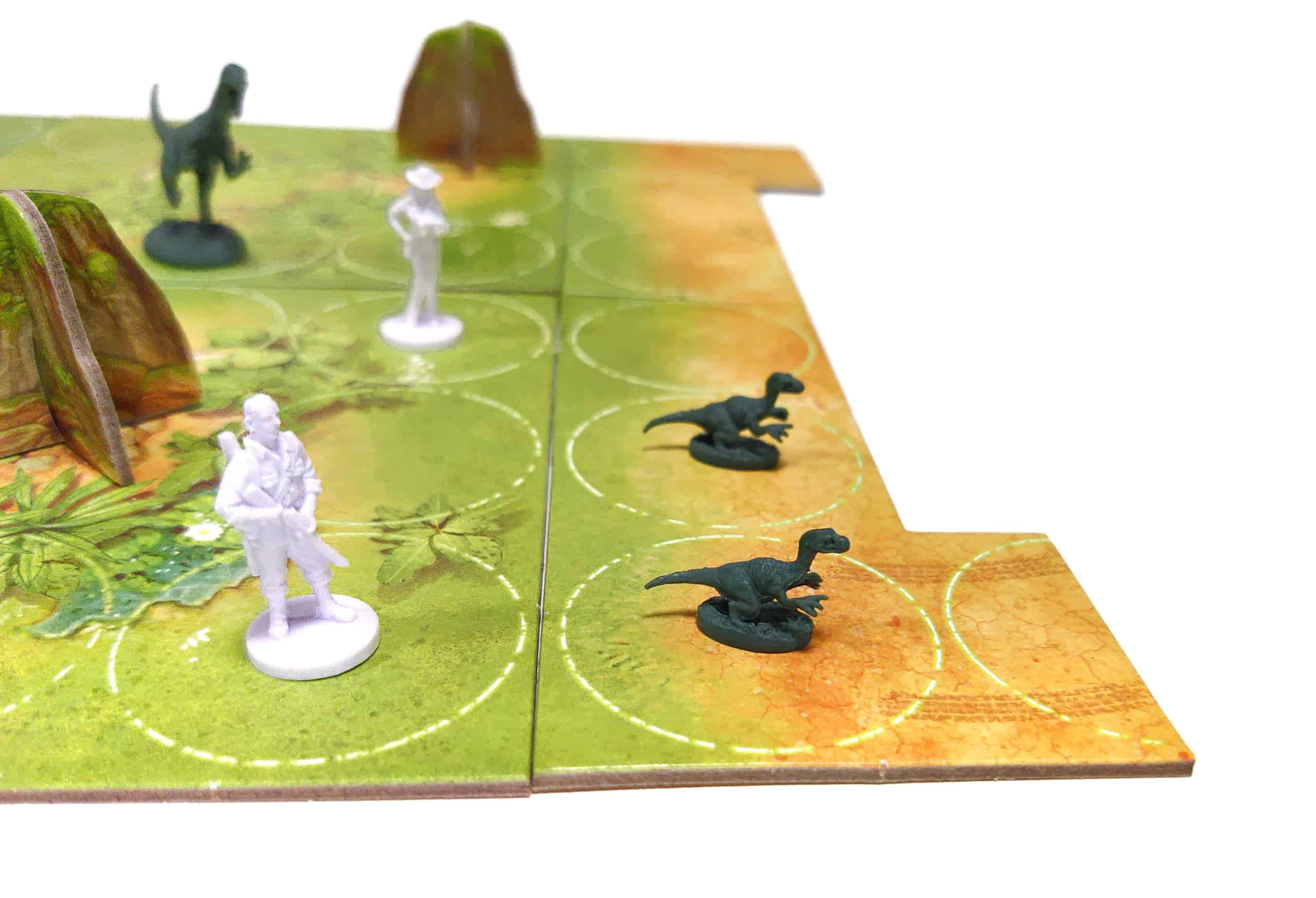 Kaksi raptorinpoikasta laudan reunalla valmiina pakenemaan, mutta perässä on kaksi tieteilijää.