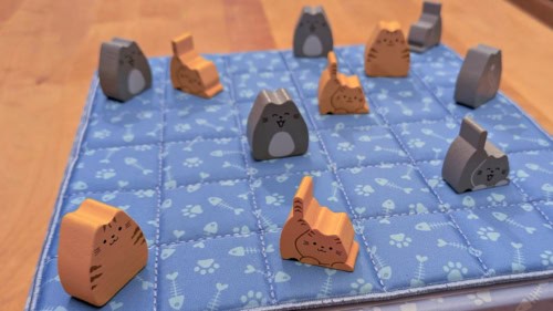 Boopin pelilautana toimii pelilaatikon päälle asetettava sininen viltti, jossa on tassu- ja kalanruotokuviota. Viltin päällä on oransseja ja harmaita kissanappuloita, sekä pienempiä pentuja että isompia aikuisia kissoja.