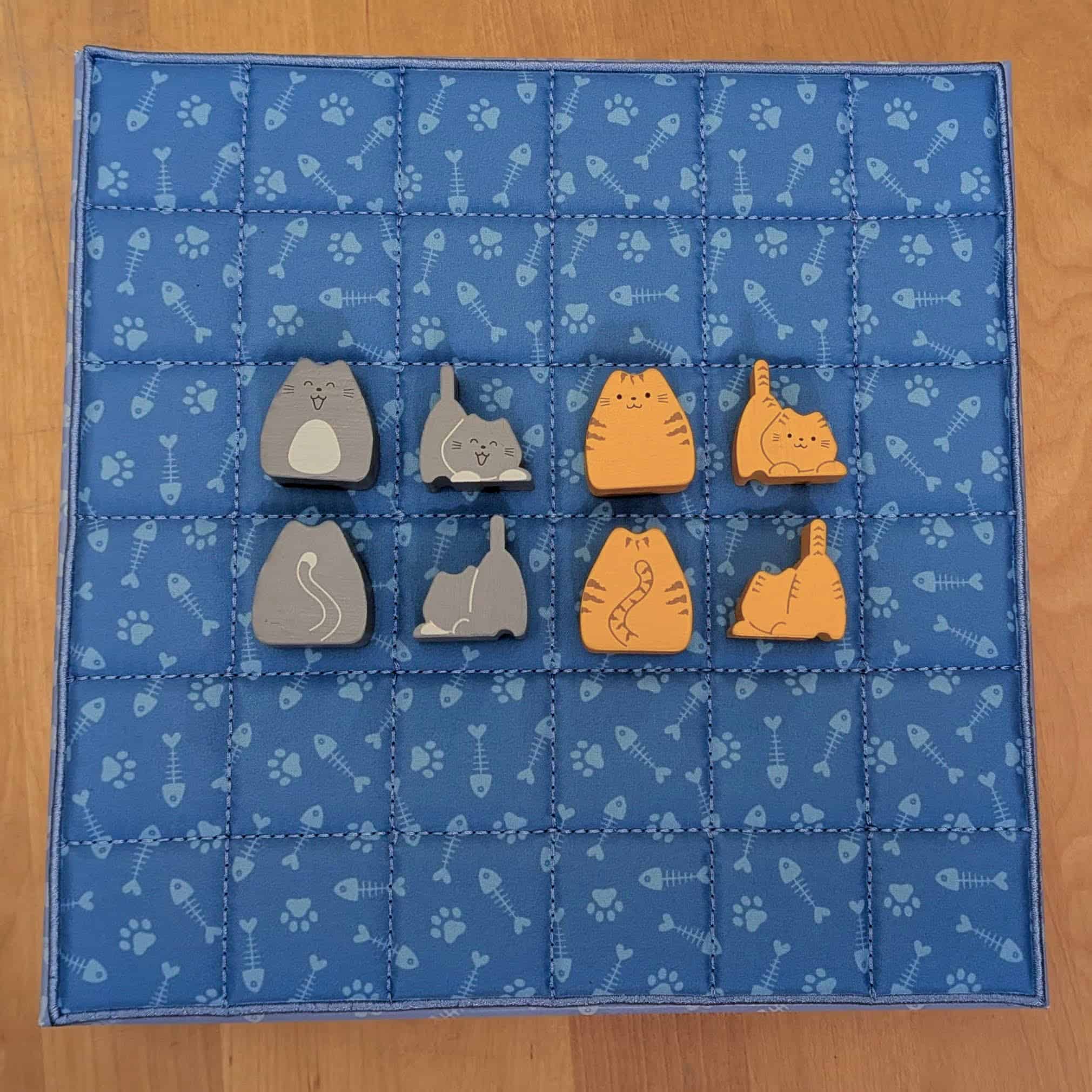 Kahdeksan kissanappulaa viltin päällä, näyttäen kummankin pelaajan pentu- ja aikuiskissojen molemmat puolet.