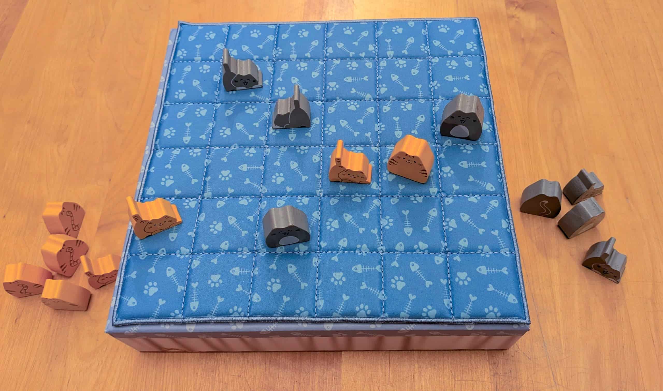 Pelin laatikko, jonka päällä on viltti ja viltillä kissanappuloita.