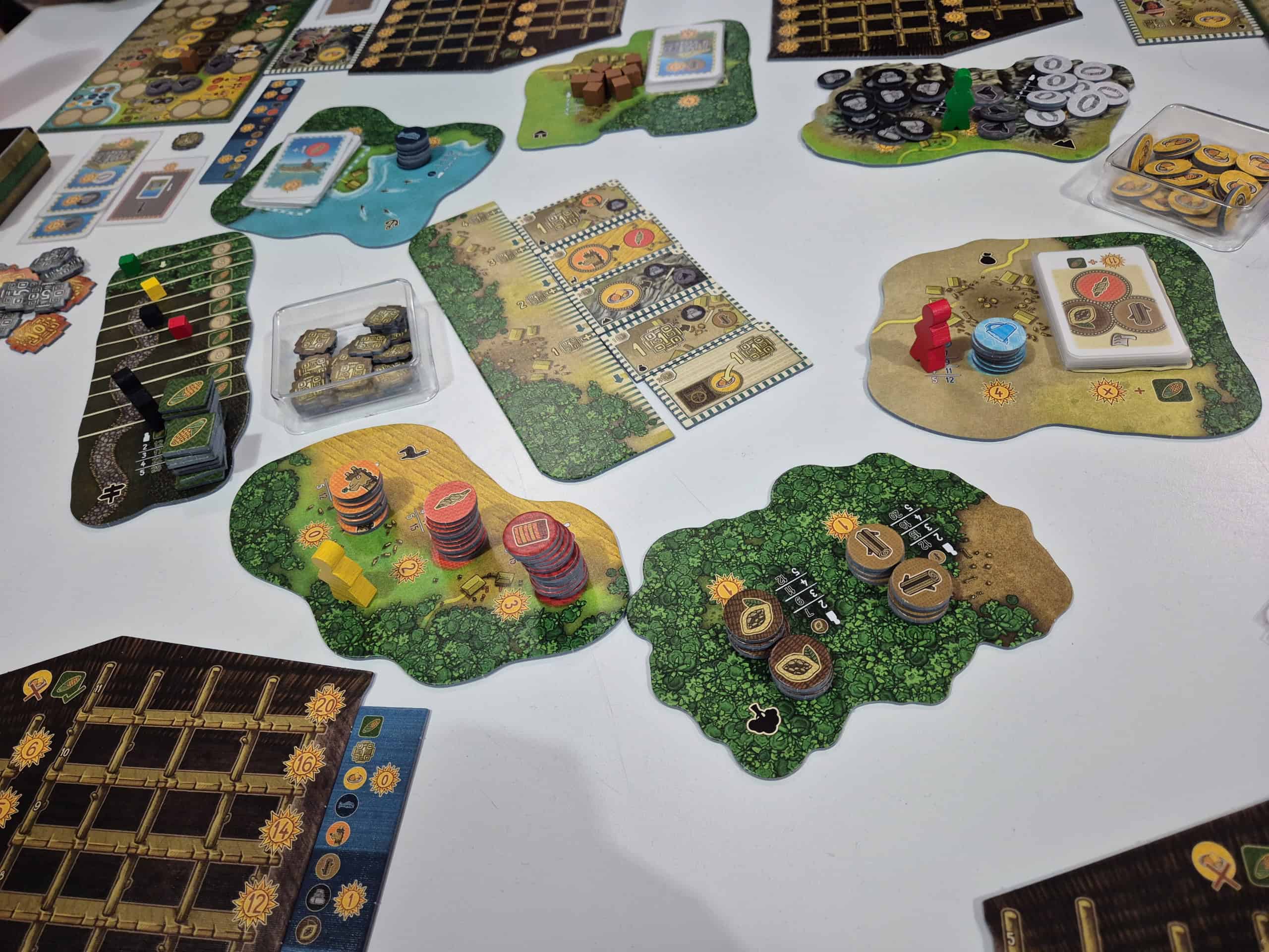 Altiplanon irtonaisista saarekkeista koostuva pelilauta pöydällä, reunalla pelaajien pelilautoja. Saarekkeilla on eri tuotteita kuvaavia pahvilätkiä pinoissa.