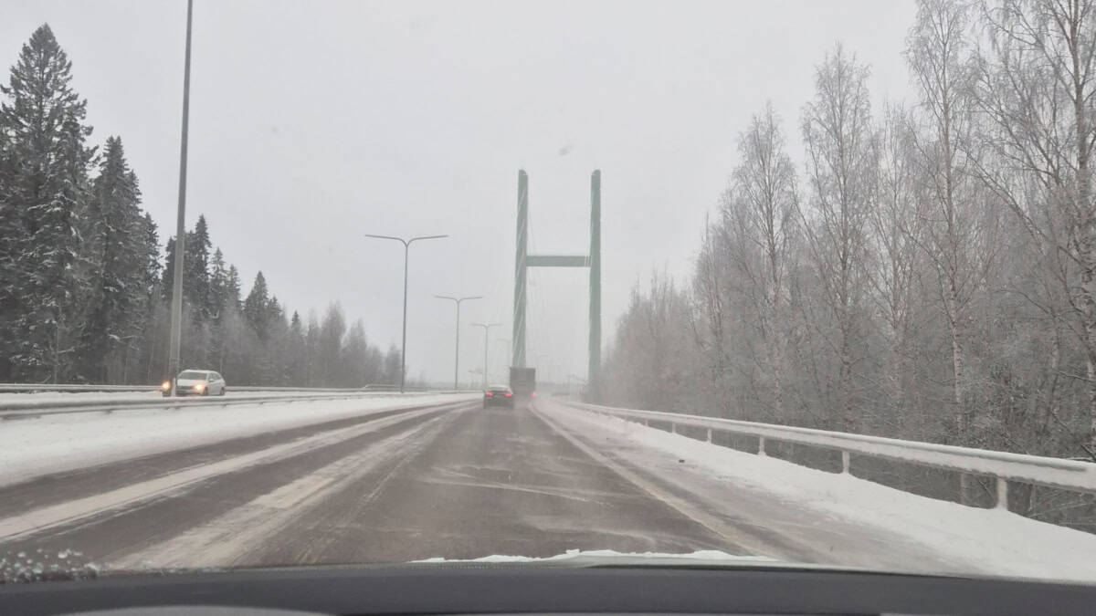 Talvinen moottoritienäkymä, taivas on tasaisen harmaa ja edessä on riippusillan pylväät.
