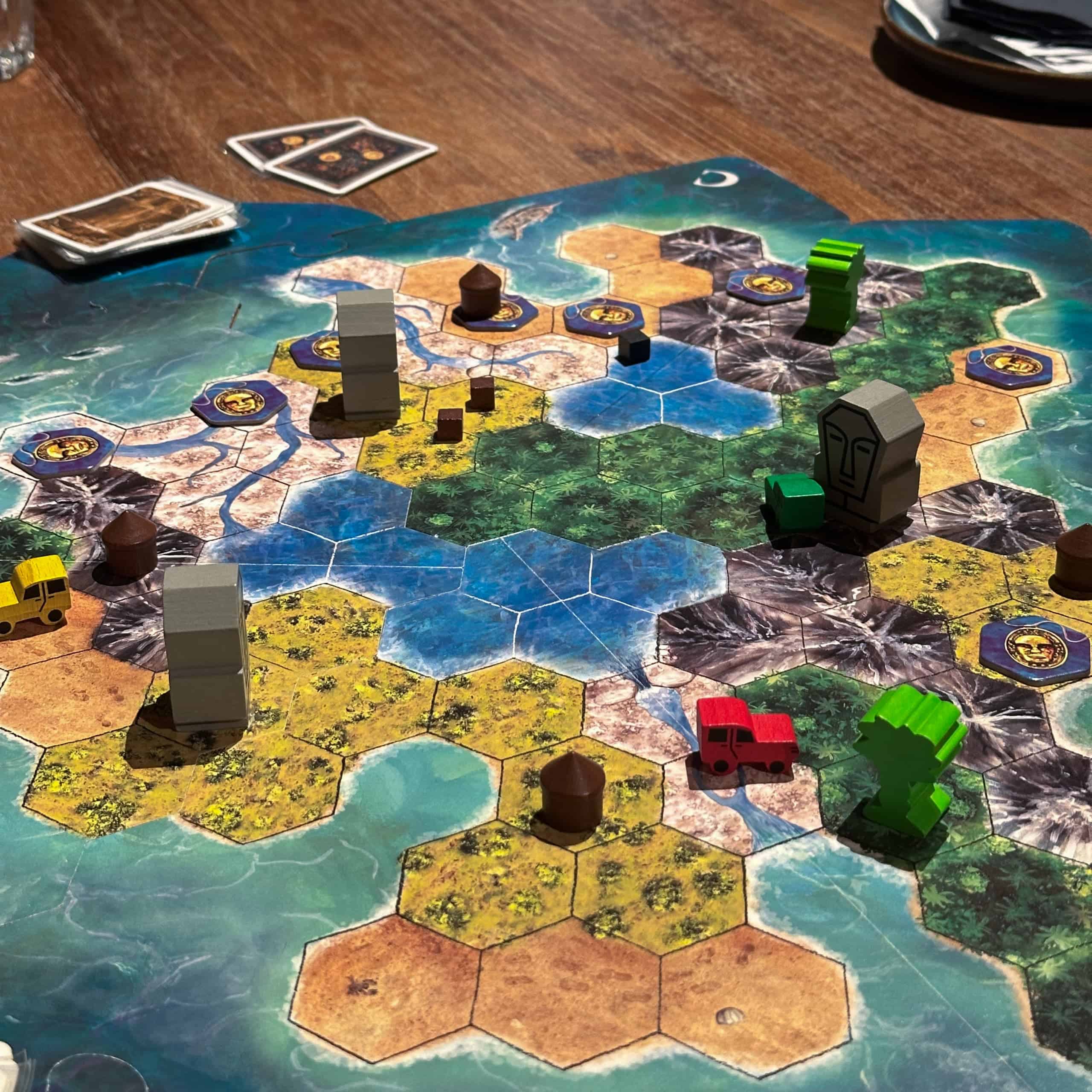 Lähikuva Tobagon pelilaudasta, joka on heksaruuduista koostuva saarimaisema, jossa on erilaisia maastotyyppejä ja puisia nappuloita.