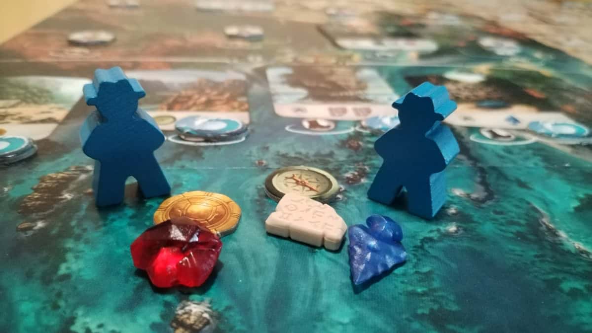 Kaksi Arnakin sinistä löytöretkeilijänappulaa pelilaudan päällä, välissään Arnakin resurssinappuloita.