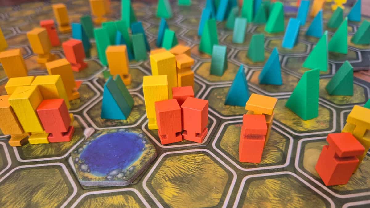 Lähikuva Aspensin pelilaudasta. Vihreänruskeassa heksaruudukossa on ruuduissa vaihteleva määrä joko keltaisen- ja oranssinsävyisiä laatikkomaisia lehtipuita tai vihreitä kolmiomaisia havupuita.