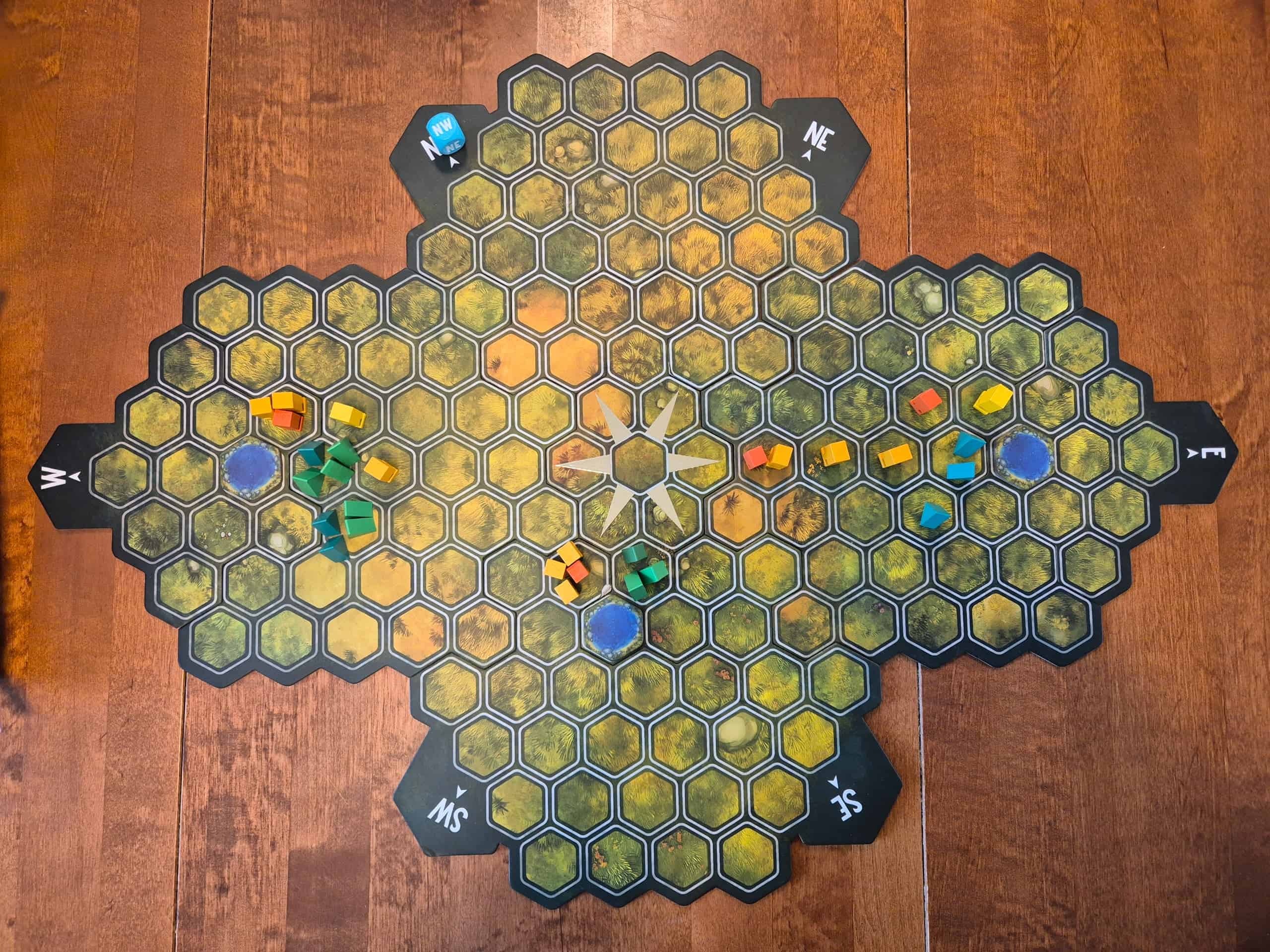 Aspensin pelilauta lintuperspektiivistä. Lauta muodostuu 148 heksaruudusta, jotka ovat leveän ristin muodossa. Keskellä on kompassiruusu. Laudalla on kolme vesiheksaa, joiden ympärille pelaajat ovat alkaneet lisätä puita.