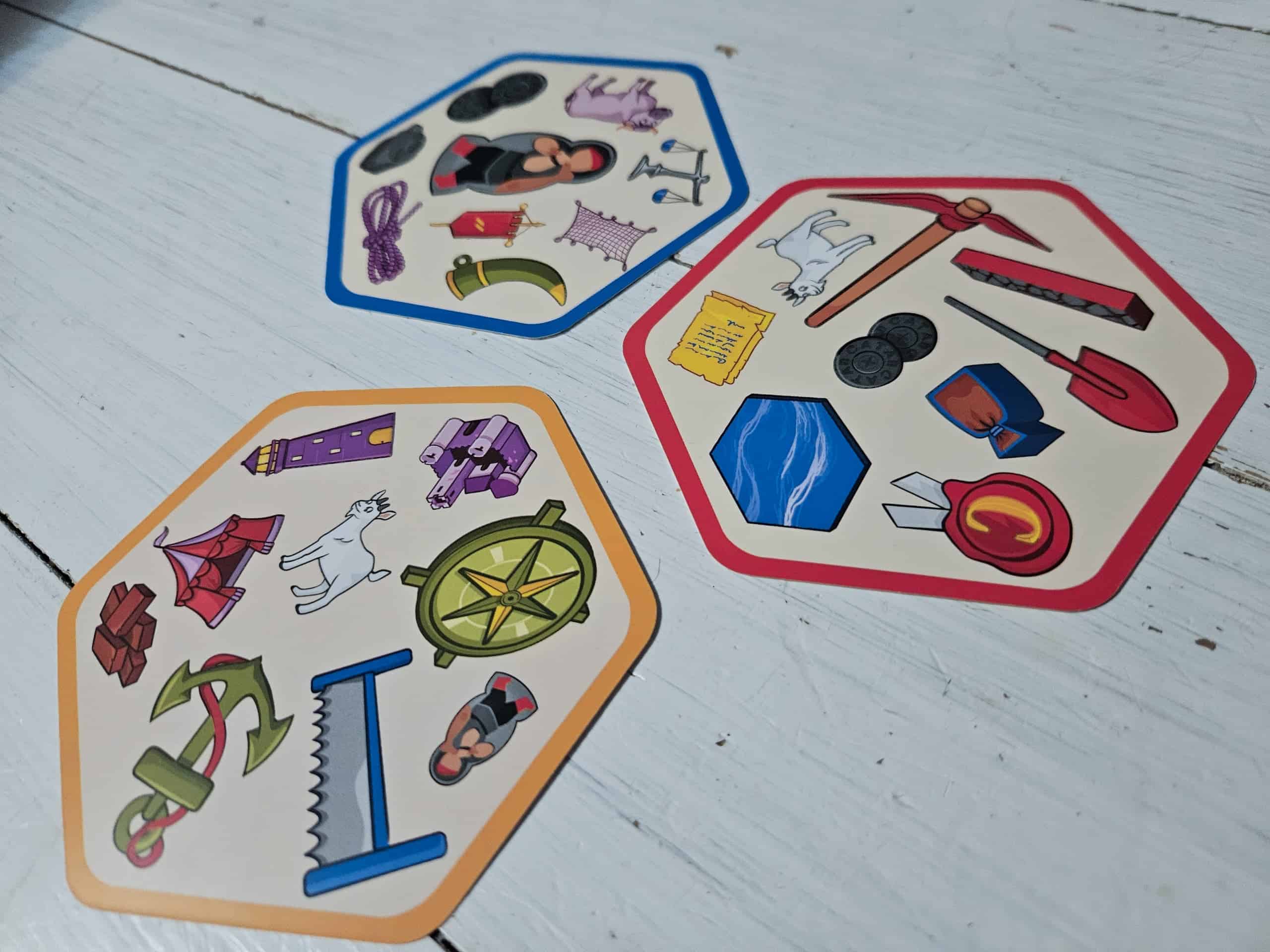 Kolme Dobble Catanin korttia, joilla on eri väriset reunat: sininen, punainen ja keltainen.