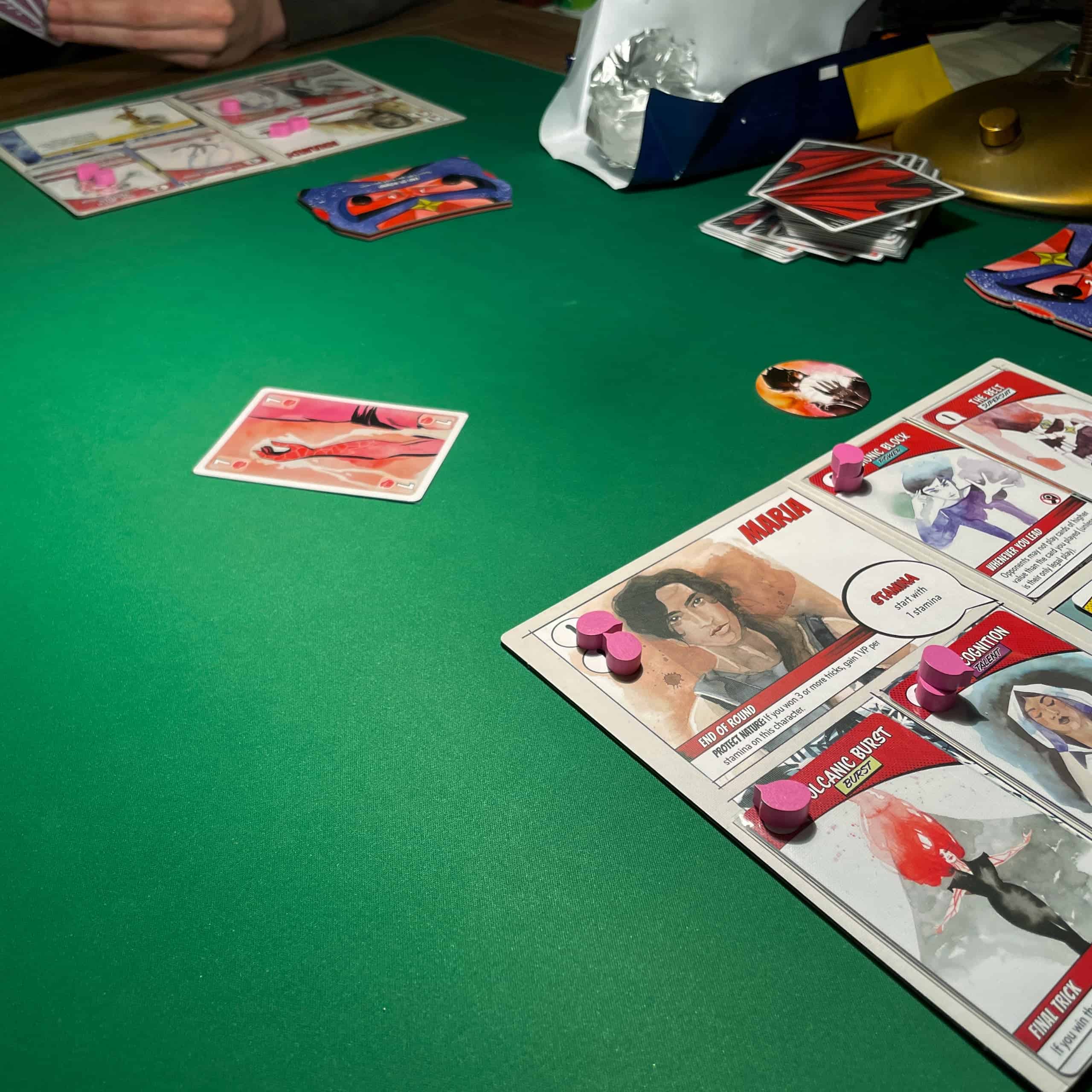 Peli Origin Storya menossa. Etualalla Marian hahmolauta, taaempana näkyy toisen pelaajan hahmolauta ja käsi. Pöydällä on yksi pelattu kortti. Taaempana näkyy Fazerin avattu suklaalevy.