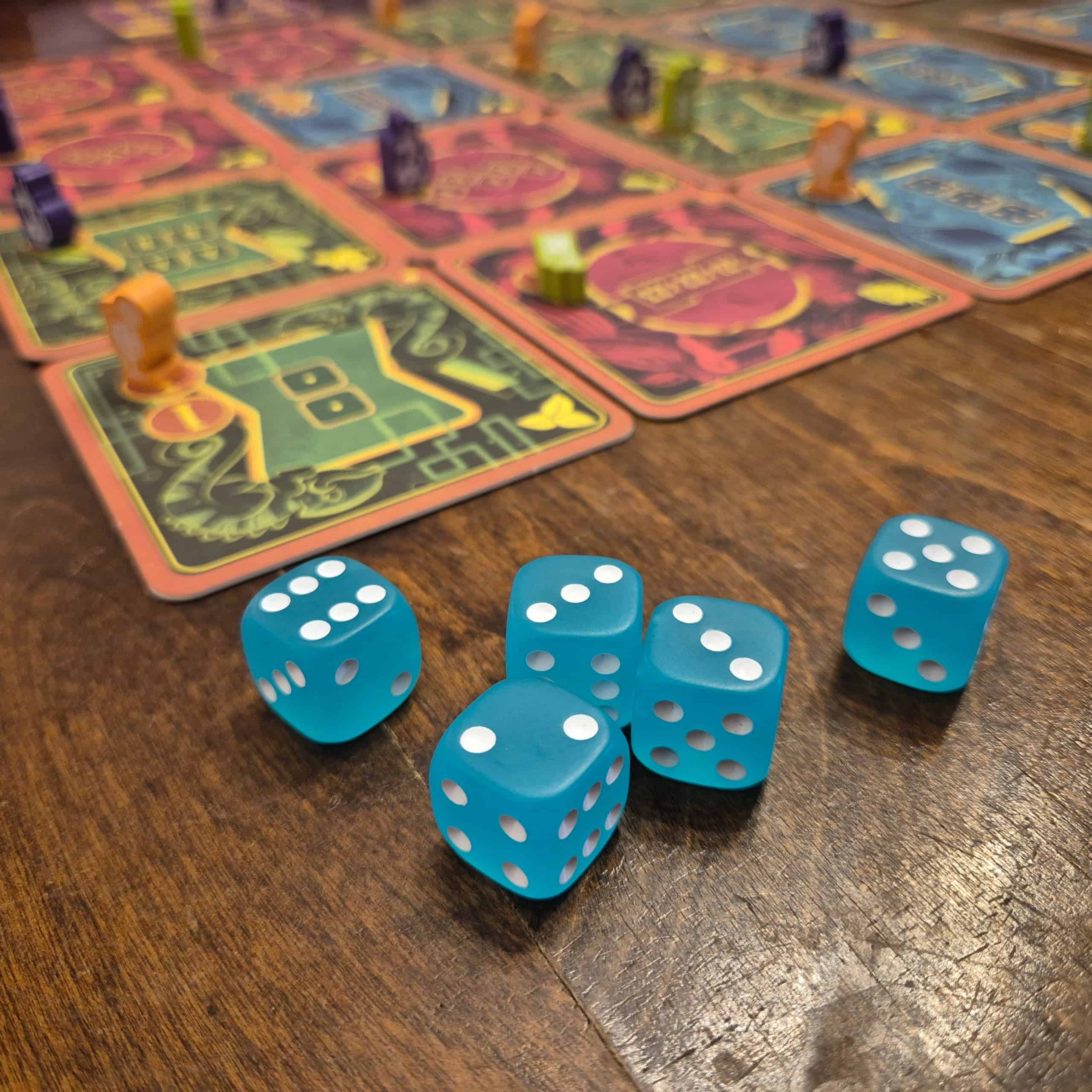 Lähikuvassa Piña Coladicen turkooseja noppia, taustalla lasinalusista koostuva pelilauta, jossa on pelaajien nappuloita.