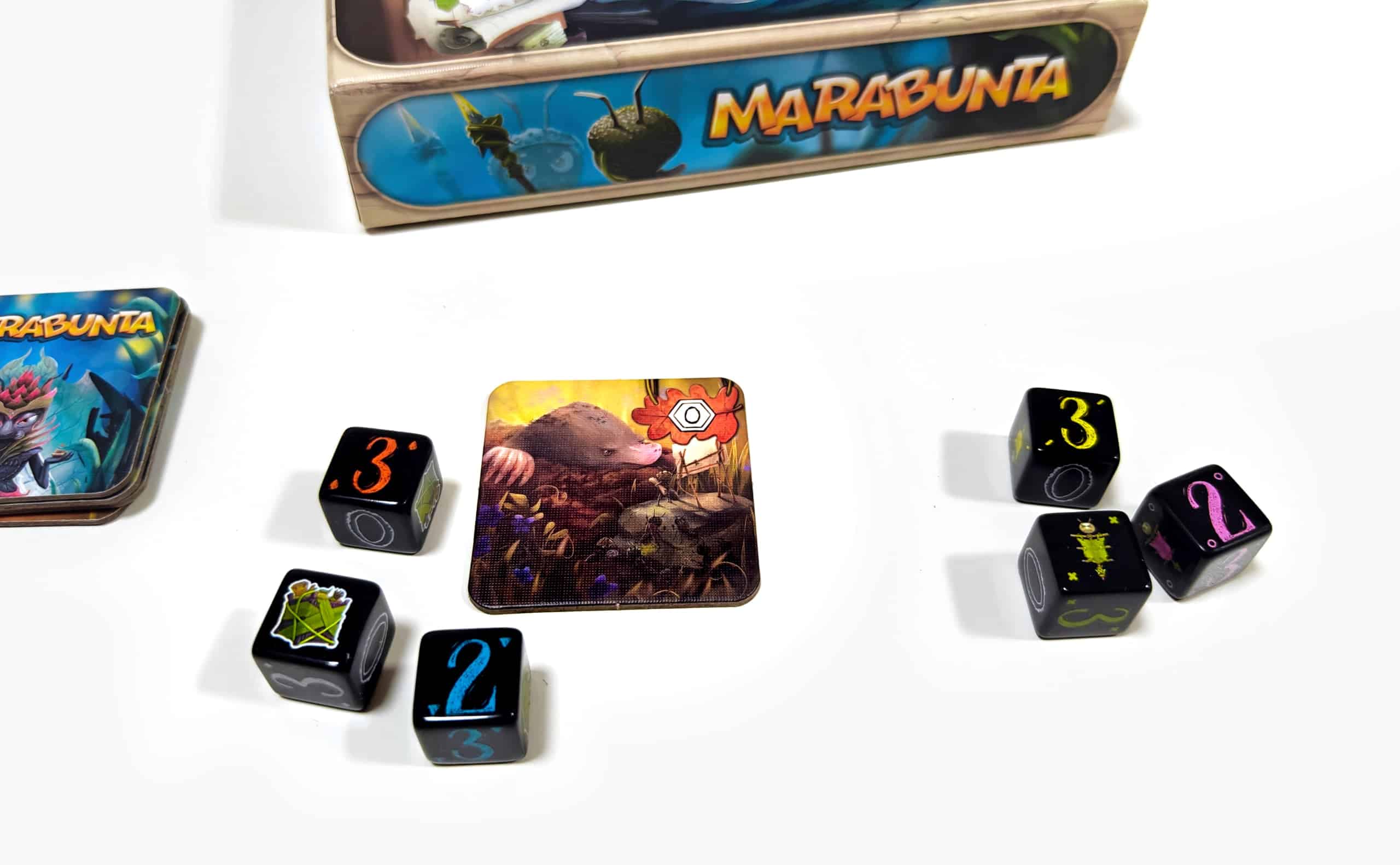 Jako, jossa toisella puolella myyrälaatta ja nopat 3, 2 ja laatikko, toisella puolella 3, 2 ja lippu.