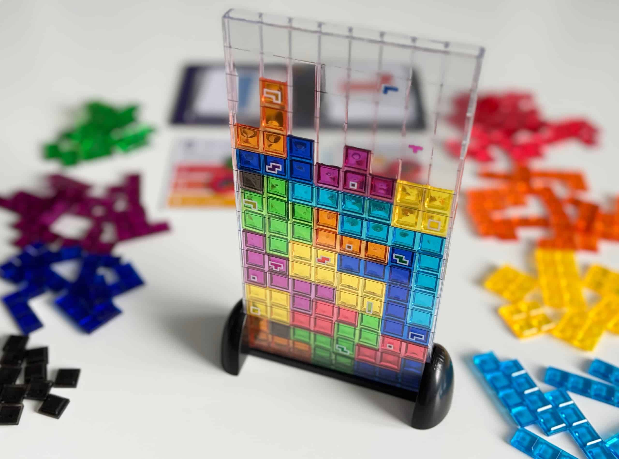 Tetris-pelin matriisi eli läpinäkyvä muovinen teline, johon palasia pudotellaan. Tornissa on jo yksitoista riviä täynnä. Ympärillä on erivärisiä palasia.