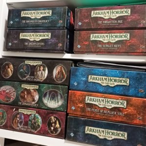 Arkham Horror -korttipelin laatikoita kirjahyllyssä.