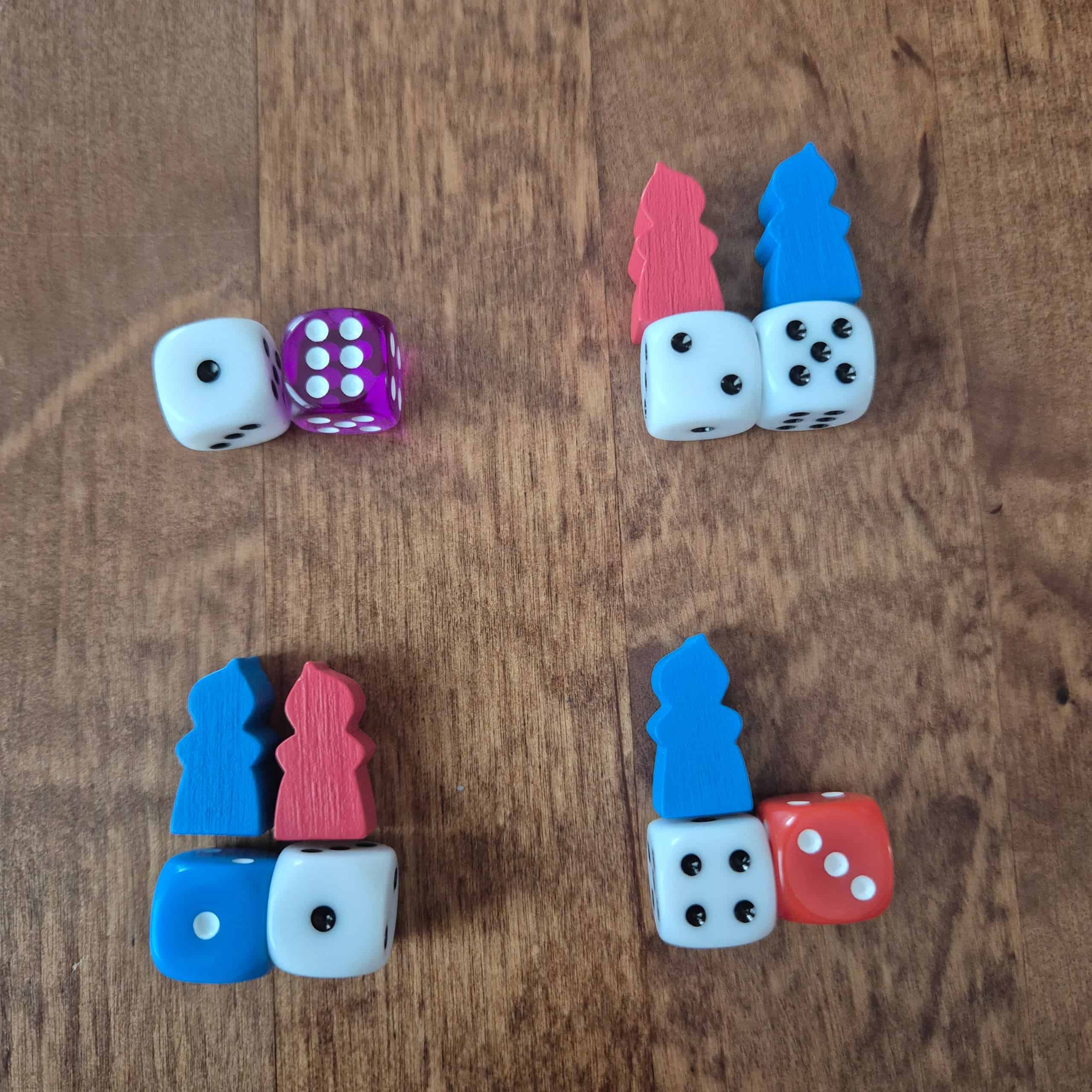 Neljä noppa- ja meeplesettiä: valkoinen 1 ja violetti 6, valkoiset 2 ja 5 punaisella ja sinisellä meeplellä, sininen 1 sinisellä meeplellä ja valkoinen 1 punaisella meeplellä ja punainen 3 ja valkoinen 4 sinisellä meeplellä.