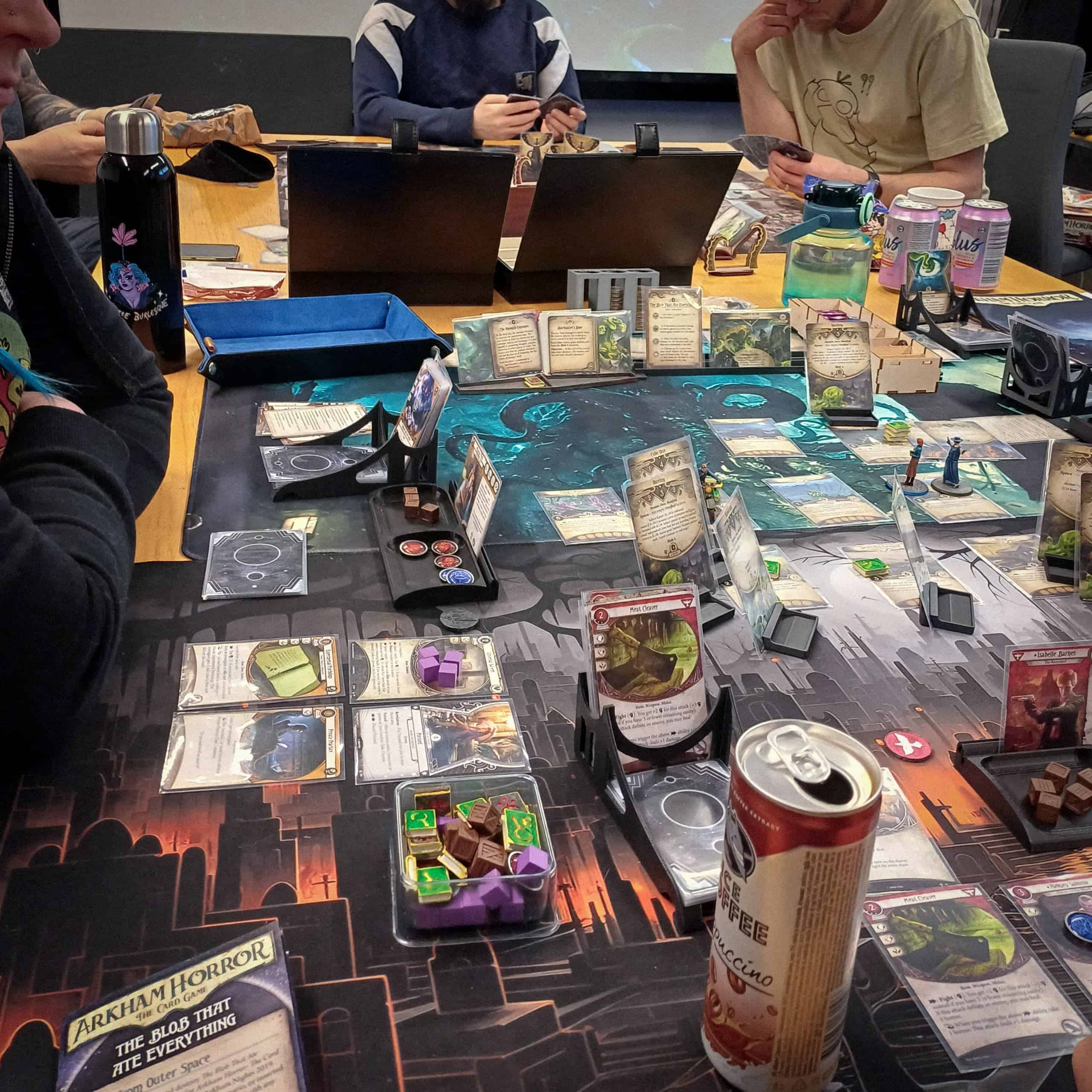 Pöytä täynnä Arkham Horror LCG:n komponentteja ja pelimattoja.