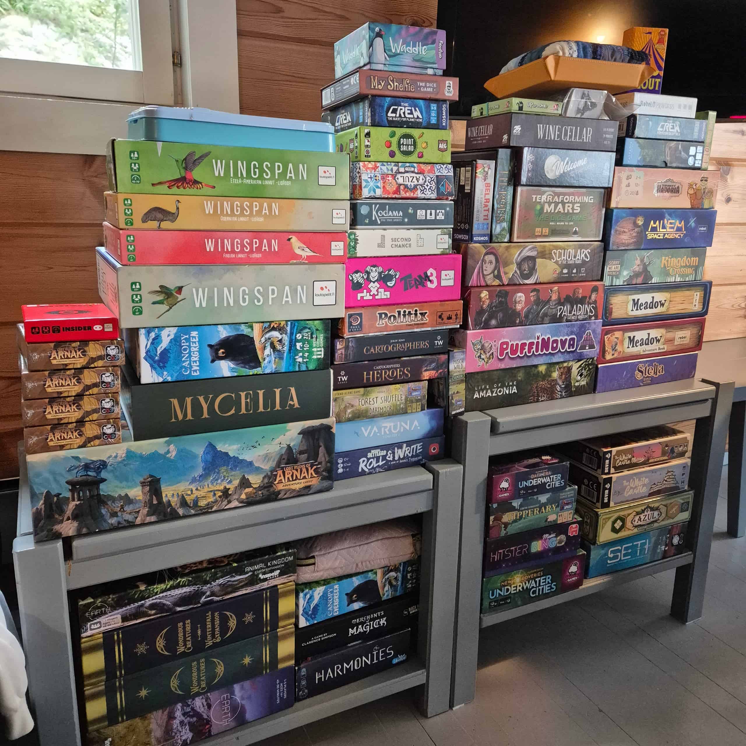 Kuutisenkymmentä pelilaatikkoa kahden matalan pöydän päällä korkeina torneina.