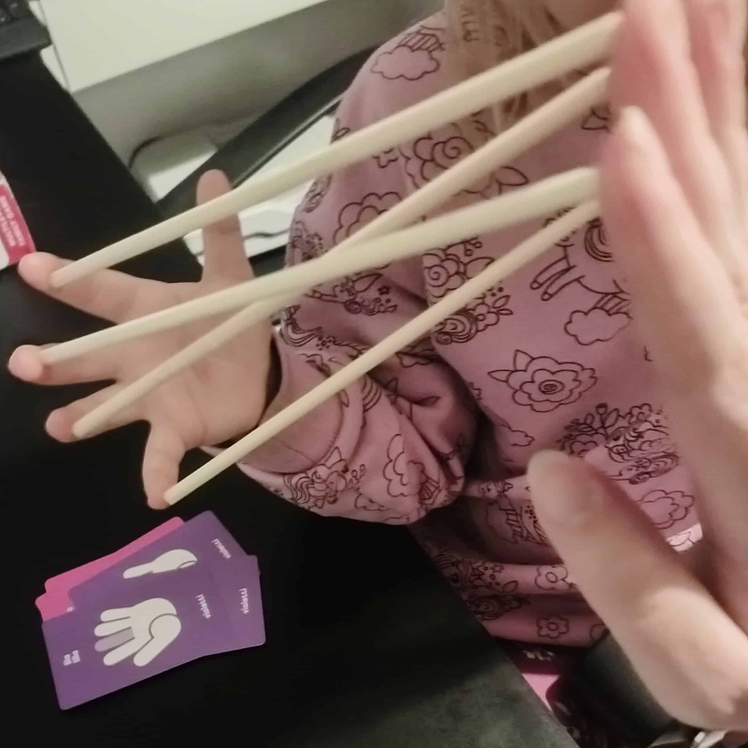 Lapsen käsi, joka pitelee neljää tikkua sormenpäissä.